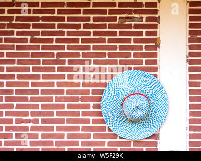 Blue straw hat hanging on a brick wall Stock Photo