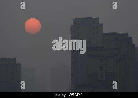 The sun and high-rise buildings are seen vaguely in heavy smog in Dalian city, northeast China's Liaoning province, 4 March 2019. Stock Photo