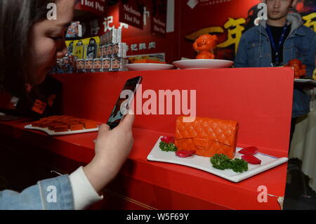 A visitor takes photos of a piquant chafing dish seasoning featuring shape of Chanel handbag during the 100th China Food and Drinks Fair in Chengdu ci Stock Photo