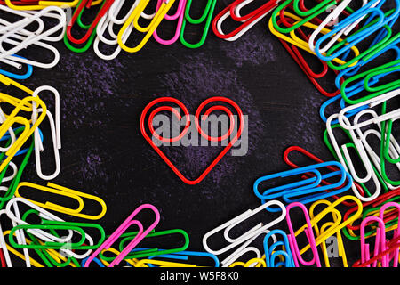 Colored paper clips isolated on dark background Stock Photo
