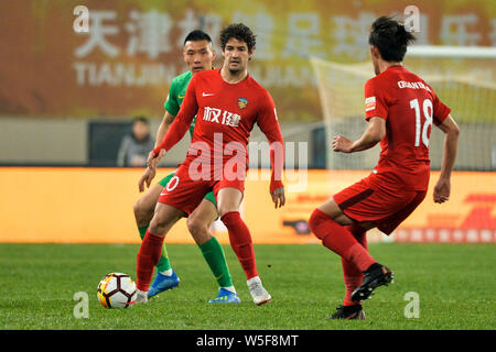 --FILE--Brazilian football player Alexandre Rodrigues da Silva, known as Pato, center, of Tianjin Quanjian dribbles against Yu Dabao of Beijing Sinobo Stock Photo