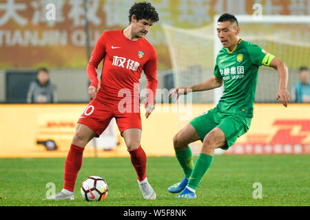 --FILE--Brazilian football player Alexandre Rodrigues da Silva, known as Pato, left, of Tianjin Quanjian dribbles against Yu Dabao of Beijing Sinobo G Stock Photo