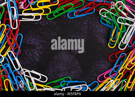 Colored paper clips isolated on dark background Stock Photo