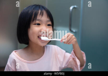 Asian Little Chinese Girl brushing her teeth in the restroom Stock Photo