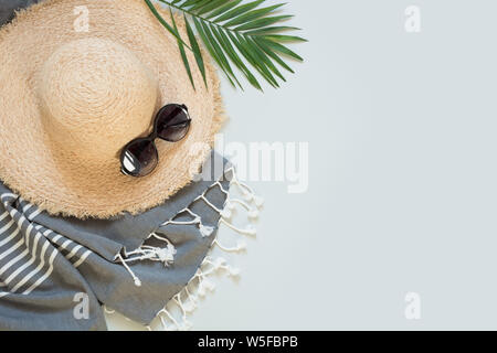 Straw beach sunhat and sun glasses on grey with space for text. Female outfit. Summer vacancy concept. Stock Photo