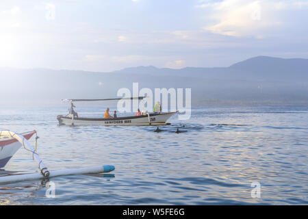 Sunrise view over tourists waiting for wild dolphin at Lovina beach in Bali, Indonesia. Stock Photo