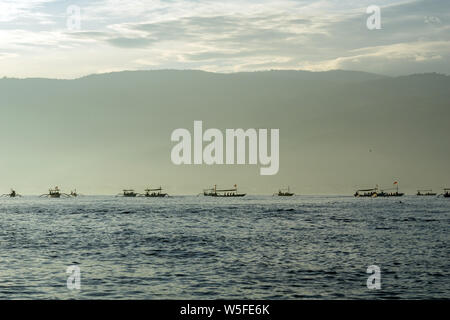 Sunrise view over tourists waiting for wild dolphin at Lovina beach in Bali, Indonesia. Stock Photo