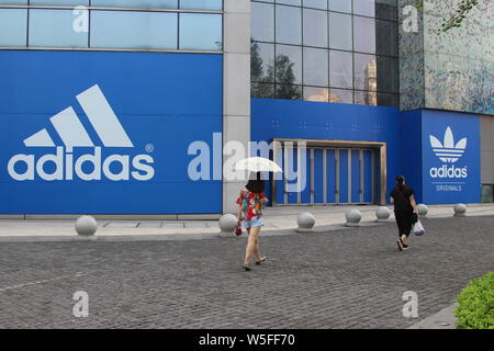 --FILE--Local residents walk past an advertisement for Adidas in Chongqing, China, 28 August 2018.   Adidas increased its currency-adjusted annual tur Stock Photo