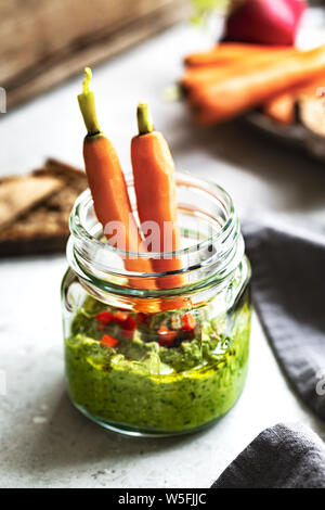 Spinach Hummus in a glass jar by baby Carrot and Rye bread Stock Photo