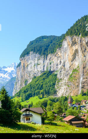 Vertical photography of picturesque village Lauterbrunnen in Swiss Alps. Famous Staubbach Falls in background. Tourists destinations in Switzerland. Summer season. Swiss landscapes. Stock Photo