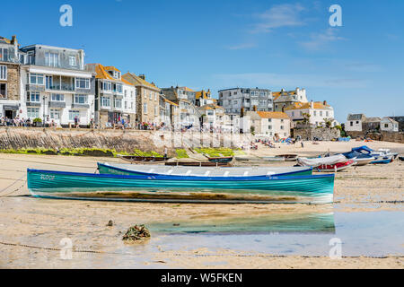 A beautiful spring day at the seaside of St Ives in Cornwall, the picture is in the harbour of two moored racing gig boats set against the quayside. Stock Photo