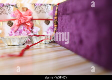 Indian festival: Raksha Bandhan background with an elegant Rakhi, Rice Grains and Kumkum. A traditional Indian wrist band which is a symbol of love. Stock Photo