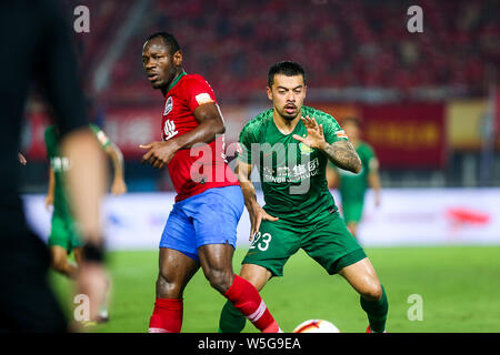 Cameroonian football player Christian Bassogog, left, of Henan Jianye passes the ball against English football player Nico Yennaris, known in China as Li Ke, of Beijing Sinobo Guoan in their 20th round match during the 2019 Chinese Football Association Super League (CSL) in Zhengzhou city, central China's Henan province, 27 July 2019. Henan Jianye defeated Beijing Sinobo Guoan 1-0.