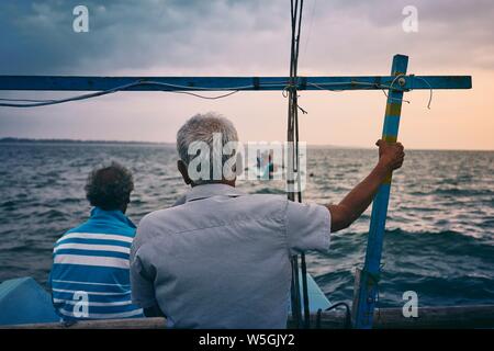 Hard work on sea. Two fishermen on fishing boat at sunrise near coastline of Sri Lanka.