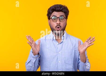 Portrait of a young Indian surprised man with dew in a shirt dosing against a yellow background. Concept of news and advertising. Stock Photo