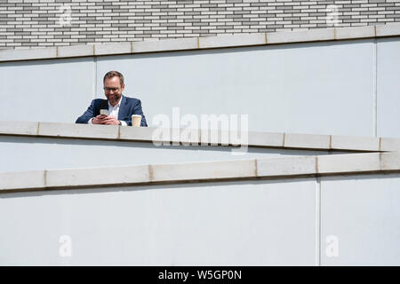 Mature Businessman Using Mobile Phone Standing Outside Office Building Stock Photo