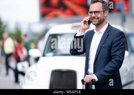 Mature Businessman Taking Phone Call On Mobile Standing By Taxi Rank Outside Railway Station Stock Photo