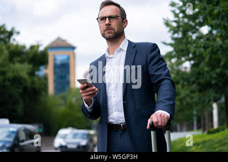 Mature Businessman Ordering Taxi Using Mobile Phone App Stock Photo