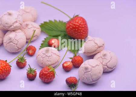 little meringues with strawberries on colored background Stock Photo