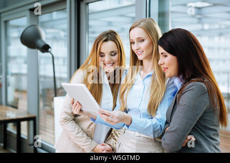 Three smiling business associates looking at a website on a tablet Stock Photo