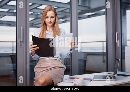 Attractive businesswoman reading business documents at office Stock Photo