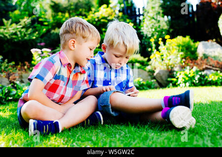 Young boys playing on smartphone at garden Stock Photo