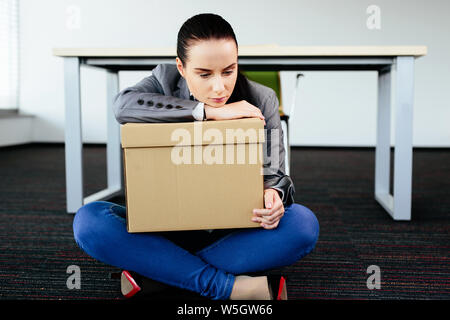 Photo of a depressed woman sitting on the floor after being let go from work Stock Photo