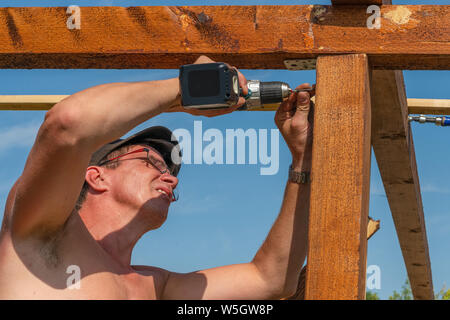 a craftsman build summer house wtih cordless screwdriver Stock Photo