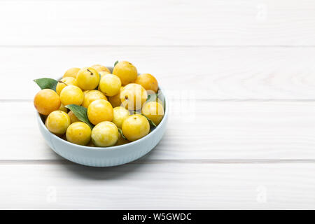 Yellow plum mirabelle fruit in bowl on white wooden table. Copy space. Healthy food Stock Photo