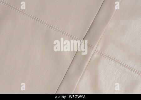 Beige leather stitched surface. Diagonal lines with copy space. Abstract background material. A good quality sewing. Stock Photo