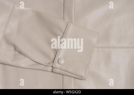 Leather beige sleeve on a stitched material. A sample of good quality sewing. Hand made clothing product. Cuff closeup. Stock Photo