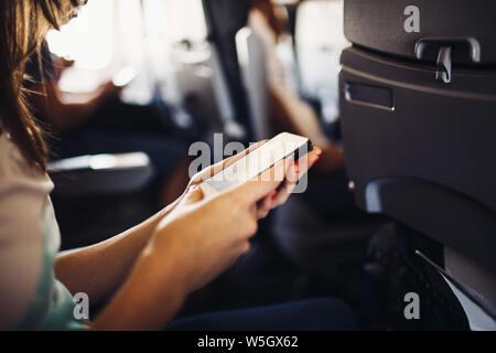 Young woman using smartphone during flight Stock Photo