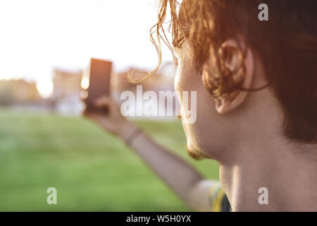 close-up guy takes pictures of nature, beautiful views on his smartphone. summer mood Stock Photo