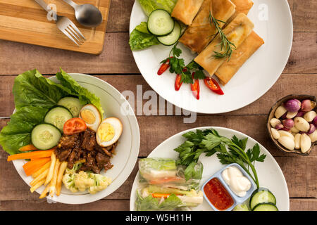 Asian style spring rolls  with mixed vegetables and satay beef on table - layflat food concept image Stock Photo