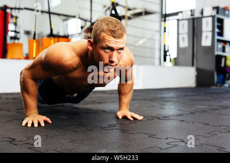Young muscular athlete doing suspension pushups Stock Photo