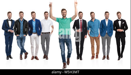 Positive young man gesturing peace and walking forward in front of team of himselfs posing in different positions and outfits, on white background Stock Photo