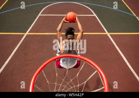 African young basketballer making effort while throwing ball in basket Stock Photo