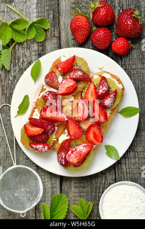 Strawberry bruschetta with kiwi and cream cheese, top view. Easy summer dessert Stock Photo