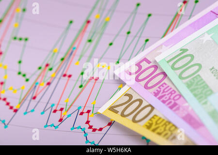 heap of many Euro currency banknotes with financial chart of stock market Stock Photo