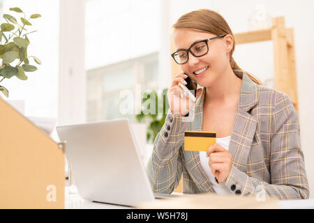 Pretty well-dressed businesswoman talking to online shop manager on mobile phone Stock Photo