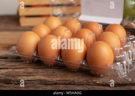Close up eggs of chicken in a plastic box placed on a wooden table. Select focus shallow depth of field. Stock Photo