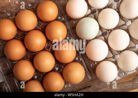 Close up full frame eggs of chicken and duck in plastic box on the wooden table. Stock Photo