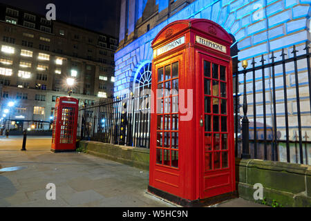 Classic Red British telephone boxes at the side of an illuminated Liverpool Town Hall Stock Photo