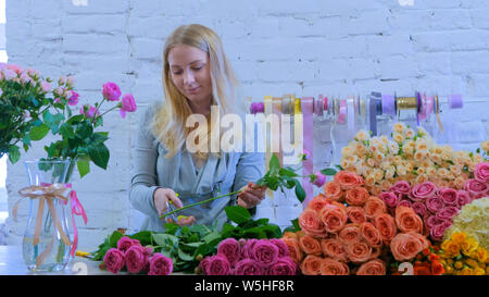 Professional florist working with flowers at studio Stock Photo