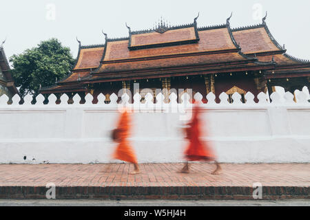 Buddhist monks during Laotian traditional sacred alms giving ceremony in Luang Prabang city, Laos. Long exposure, blurry object Stock Photo