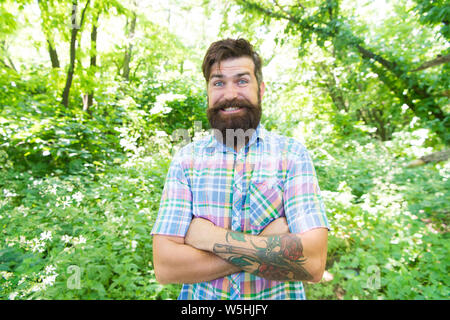 Emotional nature lover. Man bearded hipster green trees background. Guy relax in summer nature. Man handsome beard and mustache in summer forest. Summer vacation concept. United with environment. Stock Photo