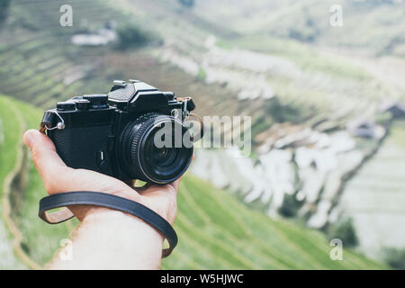 Hand holding black vintage film camera with Sapa rice terraces on background, Vietnam Stock Photo
