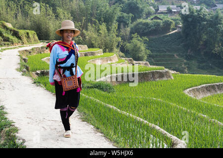 Sapa, Vietnam - May 2019: woman from Hmong ethnic group in traditional dress walking next to the rice terrace in Lao Cai province Stock Photo