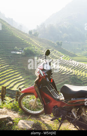 Red modern motorcycle standing next to rice terraces of Sapa in Lao Cai region, Vietnam Stock Photo