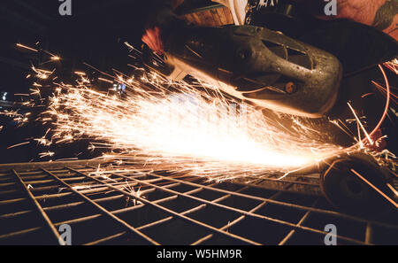 Worker Using Angle Grinder in Factory and throwing sparks. Stock Photo